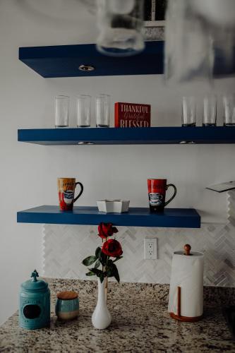 a shelf with cups and a vase with a flower on a counter at Trojan House in Ensenada