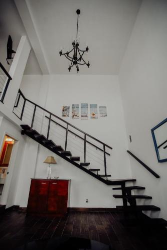 a staircase in a white room with a chandelier at Trojan House in Ensenada