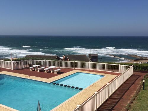 a swimming pool with the ocean in the background at Holiday unit 54 Eden Dunes in Shelly Beach
