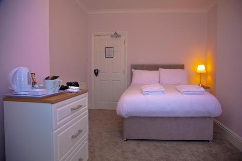 a bedroom with a bed and a desk with a microwave at Carmel House in Llandudno
