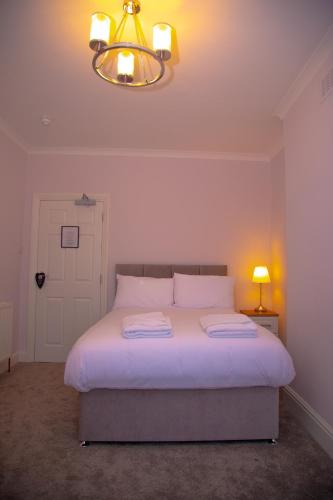 a bedroom with a large bed with a light on it at Carmel House in Llandudno