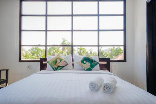 a bedroom with a white bed with a large window at Hoi An Lotus Aroma Villa in Hoi An
