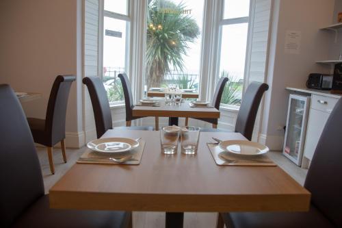 een houten tafel met stoelen en een tafel met borden en glazen bij Carmel House in Llandudno