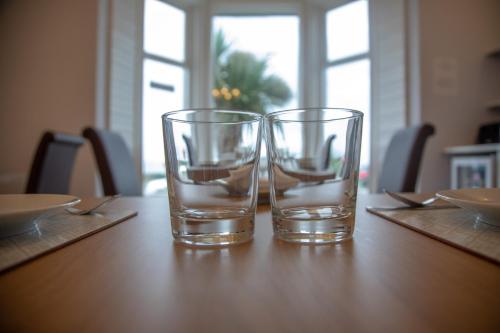 two glasses sitting on top of a wooden table at Carmel House in Llandudno