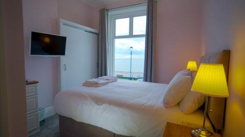 a bedroom with a bed with a window and a lamp at Carmel House in Llandudno