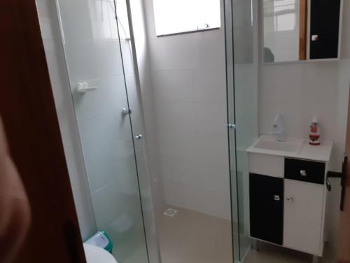 y baño con ducha acristalada y lavamanos. en Apto 2 dorm a 750m da praia, en Florianópolis