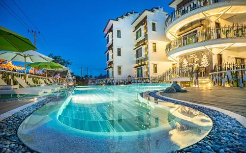 a large swimming pool in front of a building at Elites Riverside Hotel & Spa Hoi An in Hoi An