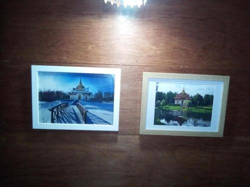 two framed photographs on a wooden table at Ban Kru Ae mixed dorm in Ban Don Muang