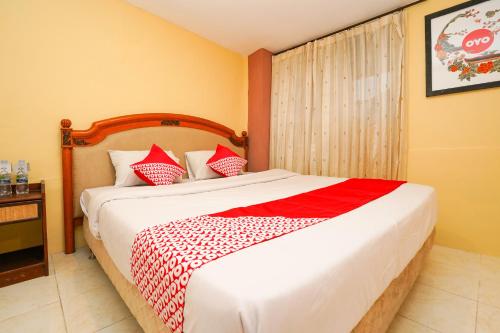 1 dormitorio con 1 cama con manta roja y blanca en SUPER OYO 710 Naomi Heritage, en Surabaya