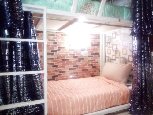 a bunk bed in a room with a brick wall at Ban Kru Ae mixed dorm in Ban Don Muang