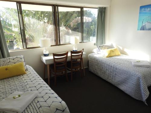 a bedroom with two beds and a desk and a window at Placid Waters Holiday Apartments in Bongaree