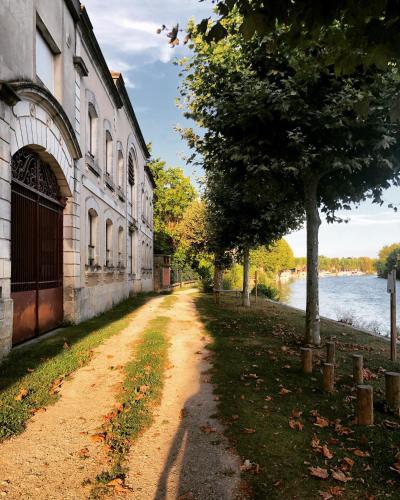 a dirt road next to a building next to a river at Studio du Cherche Midi in Jarnac