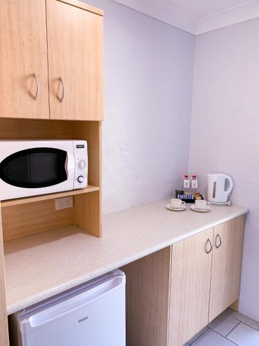 a small kitchen with a microwave on a counter at Costa Rica Motel in South West Rocks