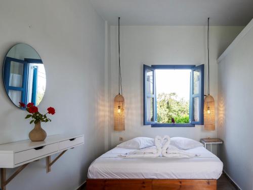 a white bedroom with a bed and a mirror at Aeolus pool apts in Palekastron