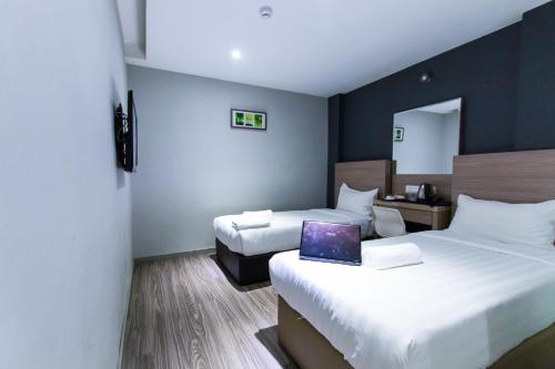 a hotel room with two beds and a laptop on the bed at Hotel 99 SS2 Petaling Jaya in Petaling Jaya