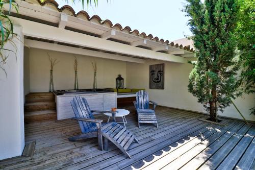 two chairs and a table on a wooden deck at Le Mas Des Brunes in Saint-Laurent-dʼAigouze