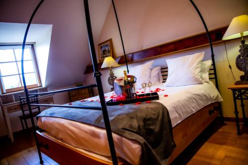 a bedroom with a four poster bed with red decorations at Hotel et Spa Le Lion d'Or in Pont-lʼÉvêque