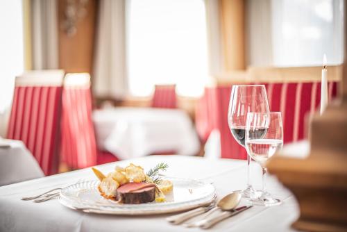 a plate of food on a table with wine glasses at Hotel Serles in Mieders