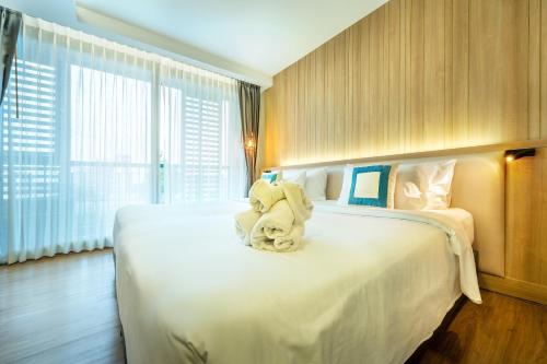 a hotel room with a bed with a stuffed animal on it at PLAAI Prime Hotel Rayong SHA Extra Plus in Rayong