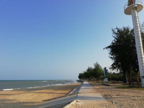 a lighthouse on a beach next to the ocean at บ้านพิม in Pran Buri