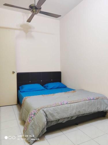 HOMESTAY GOMBAK PERMAI في بانيا إليجا: غرفة نوم مع سرير مع وسائد زرقاء ومروحة سقف