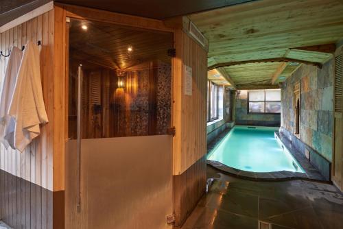 an indoor swimming pool in a house with a wooden ceiling at Hotel et Spa Le Lion d'Or in Pont-lʼÉvêque