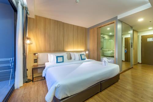 a bedroom with a large white bed and a bathroom at PLAAI Prime Hotel Rayong SHA Extra Plus in Rayong