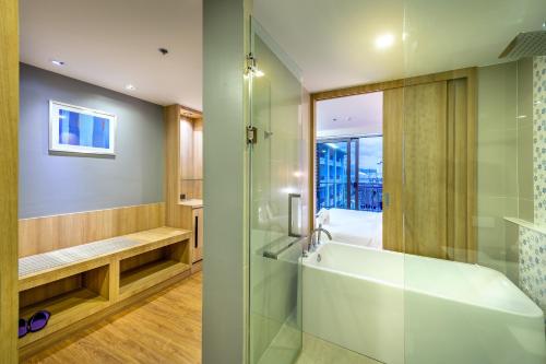 a bathroom with a tub and a glass shower at PLAAI Prime Hotel Rayong SHA Extra Plus in Rayong