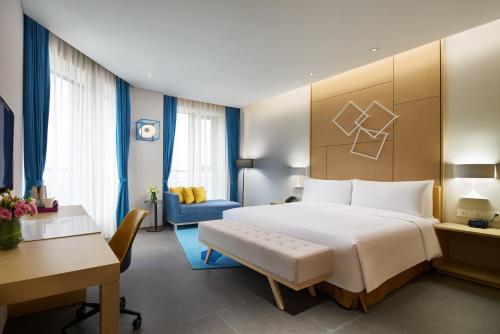 a hotel room with a large bed and a desk at Q Hotel Haikou Meilan in Haikou