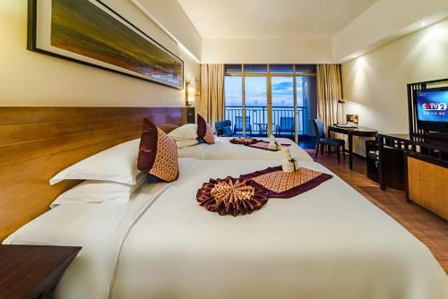a hotel room with two beds and a television at Shengyi Holiday Villa Hotel in Sanya