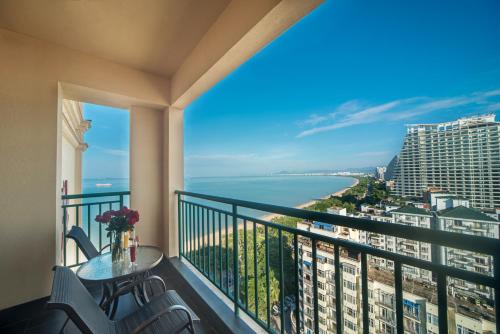 a balcony with a table and chairs and a view of the ocean at Shengyi Holiday Villa Hotel in Sanya