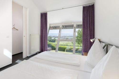 a bedroom with a white bed and a large window at Berger Hof in Kressbronn am Bodensee
