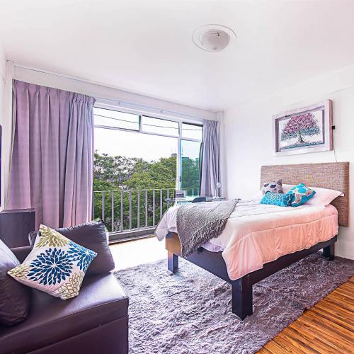 a bedroom with a bed and a window and a couch at Roma Sur Apartments with Balcony - Family Friendly in Mexico City