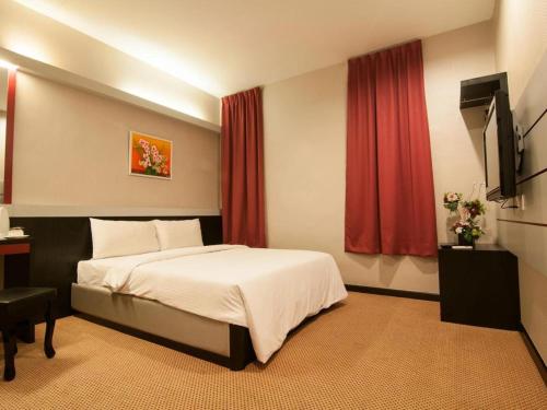 a bedroom with a bed and a desk and a television at De' Songket Hotel in Melaka