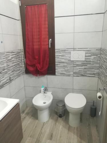 a bathroom with a toilet sink and a red shower curtain at Domos Loru in Sestu