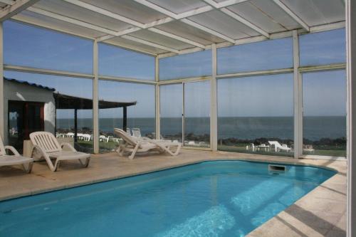 a swimming pool with chairs and a view of the ocean at Club Hotel Casapueblo in Punta del Este