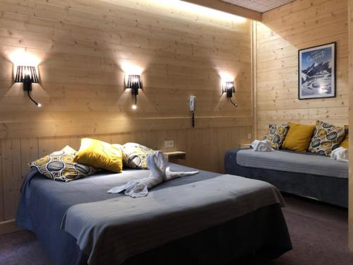 Cette chambre comprend 2 lits et 2 lumières sur le mur. dans l'établissement Hôtel Astérides Sacca, à Cauterets