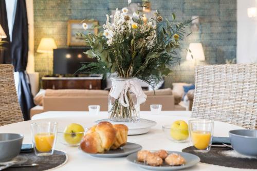 une table avec un vase de fleurs et de nourriture dans l'établissement Sweet Home Paramé Saint Malo Petite vue mer, à Saint-Malo