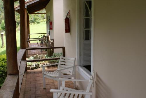 two white chairs sitting on the porch of a house at Hotel Fazenda São Francisco in Cunha
