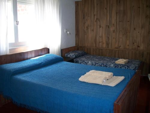 a bedroom with two beds with blue sheets and a window at Hotel Royal in San Clemente del Tuyú