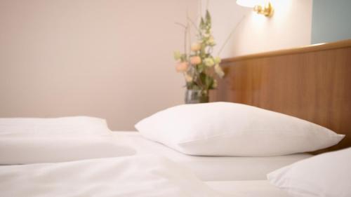 ヴェッツラーにあるHotel Blankenfeldの花瓶付きのベッドの上に白い枕2つ