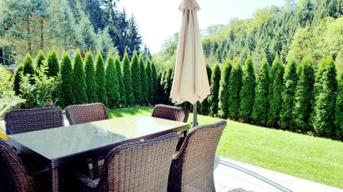 a table and chairs with an umbrella on a patio at Flamind Holiday Apartments mit Garten und Grill in Altenberg bei Linz