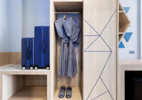 a closet with blue suitcases and a coat and shoes at BlueSotel SMART Krabi Aonang Beach - Adults only in Ao Nang Beach