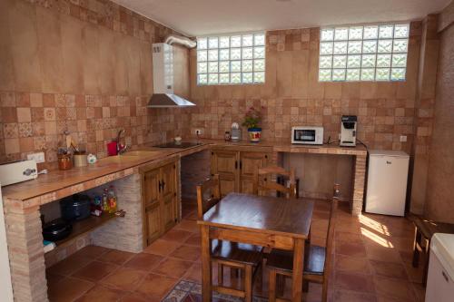 cocina con mesa de madera y cocina con nevera en Casa Rural Rosa Blanca en Los Teatinos