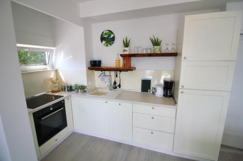 a kitchen with white cabinets and a sink at Tramontana Leeward - Cozy and charming apartment in beautiful Volosko in Opatija