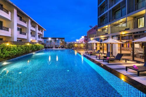 a swimming pool in a hotel at night at PLAAI Prime Hotel Rayong SHA Extra Plus in Rayong