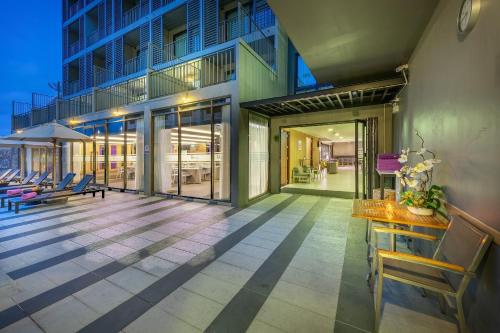 an outdoor patio with chairs and tables and a building at PLAAI Prime Hotel Rayong SHA Extra Plus in Rayong