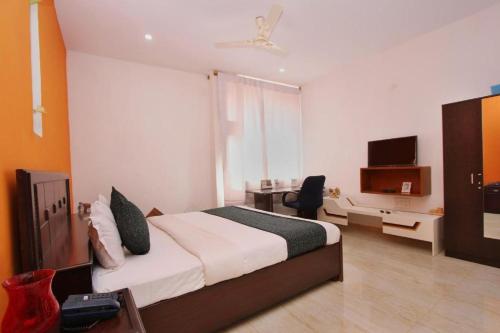 a bedroom with a bed and a desk and a television at Airport Residency in Devanhalli