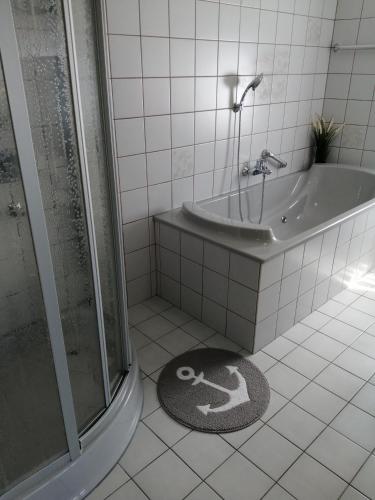 a bathroom with a shower and a tub and a rug at Steinmarner Bude in Cuxhaven