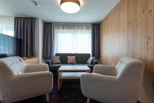 a living room with two chairs and a couch and a tv at A Casa Elegance in Längenfeld